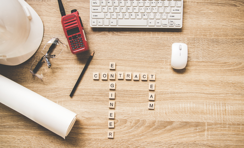 Engineering tools on work table for construction project with a white helmet, radio and blueprints. Words of engineer concepts collected in crossword with wooden cubes. Engineer Concept.