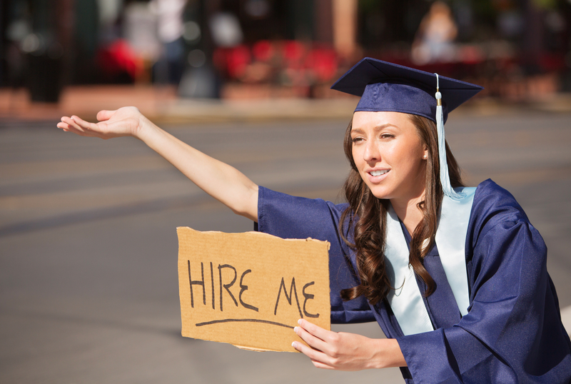 college graduate waiting to be hired with a hire me sign