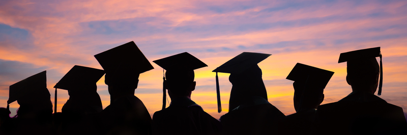 graduates standing in a line in front of a sunset